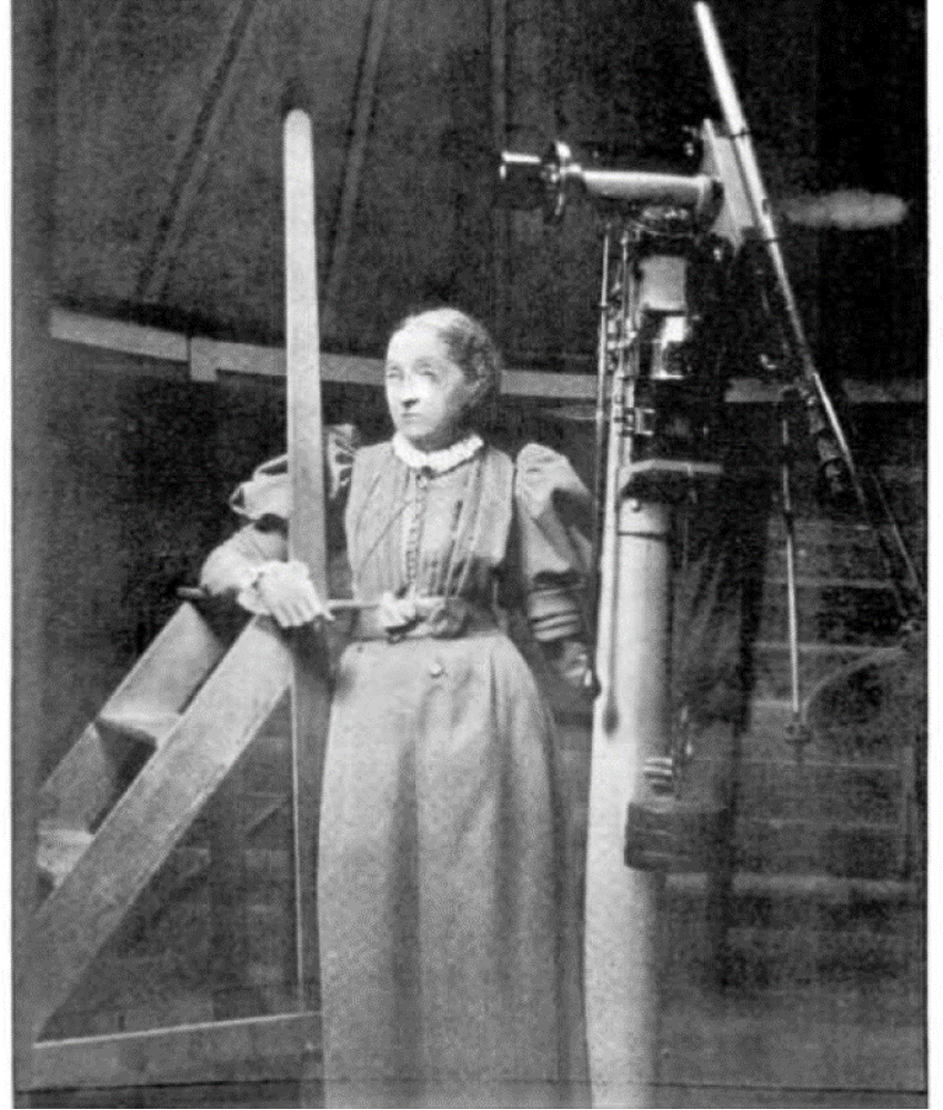 photograph of Elizabeth Brown standing next to her Wray refractor in an observatory